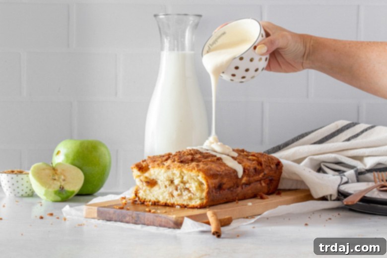 Drizzling sweet vanilla glaze over the top of a freshly baked apple fritter bread