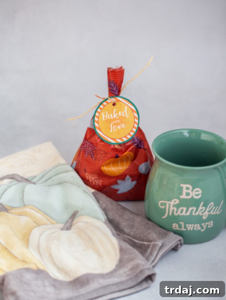 A charming 'You've Been Treated' gift bag arrangement featuring baked goods, a cozy coffee mug, and a decorative dish towel.