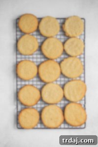 Baked peanut butter cookies perfectly golden and cooling on a wire rack, awaiting their spooky mummy decorations.