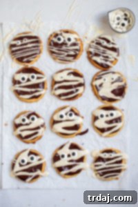 Beautifully decorated mummy cookies for Halloween, featuring a rich chocolate base, delicate vanilla glaze bandages, and fun candy eyeballs.