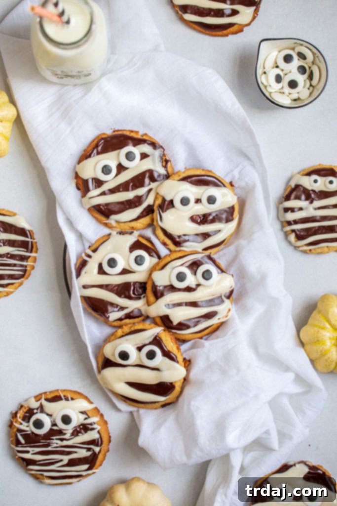 A final, enticing shot of several Peanut Butter Chocolate Mummy Cookies, perfectly decorated with chocolate ganache, vanilla glaze bandages, and charming candy eyeballs, ready for Halloween enjoyment.