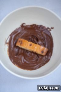 Dipping biscotti in melted chocolate.