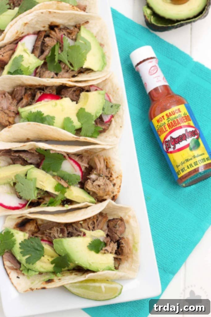 A vibrant spread of Slow Cooker Spicy Pork Carnitas with various toppings and drinks, perfect for a festive gathering.