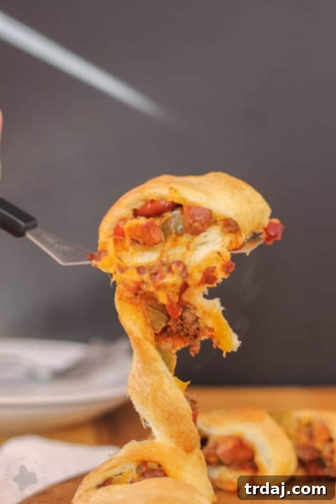 A slice of Chili Cheese Dog Crescent Ring revealing the cheesy, chili-filled interior, ready for a party.