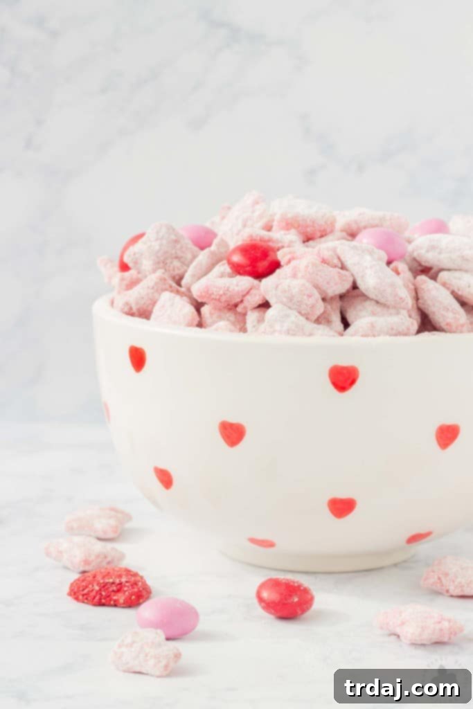 Close-up of vibrant Strawberry Puppy Chow featuring Chex cereal, pink and red candy melts, and freeze-dried strawberries