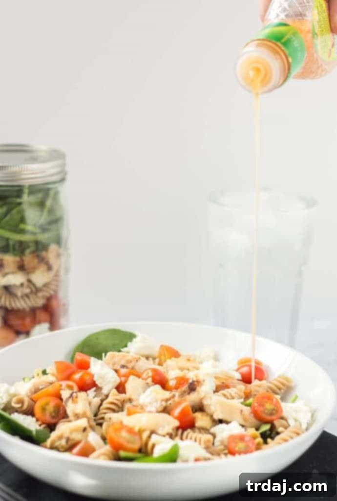 Enjoying a fresh and healthy Layered Chicken Caprese Salad in a Jar, a perfect balanced meal option.