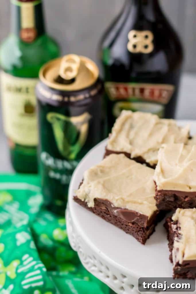 sliced Irish Car Bomb Brownies on a cake stand, showing the distinct layers of brownie, ganache, and buttercream