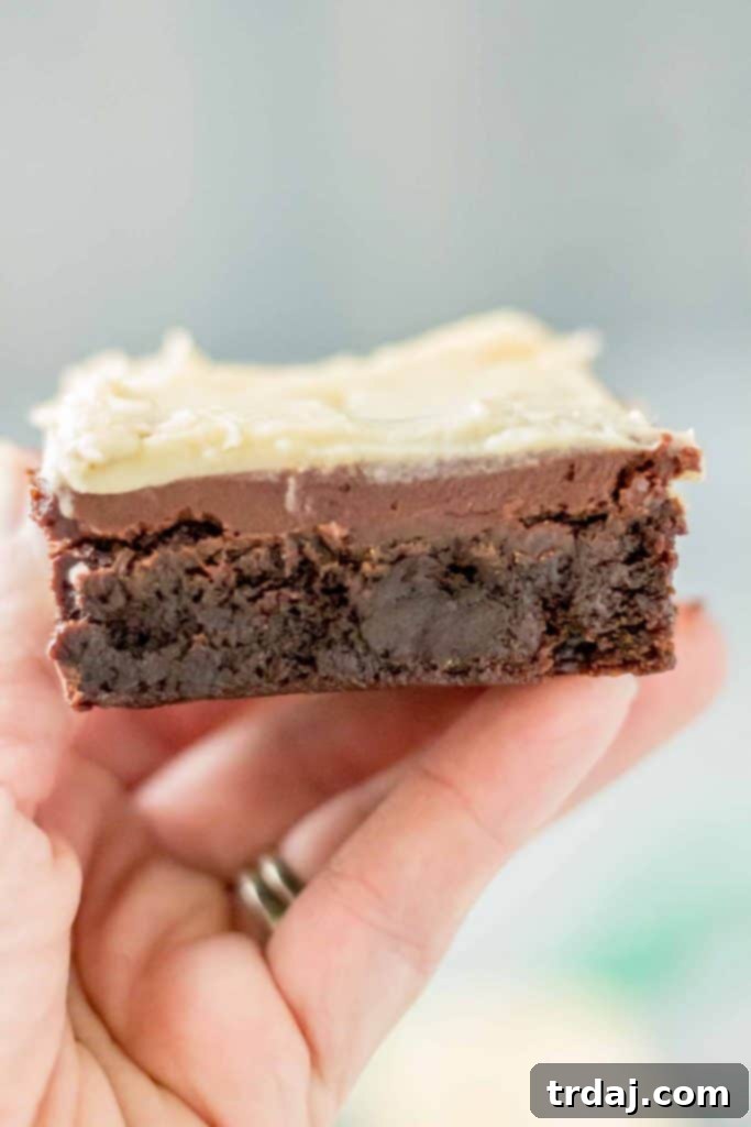hand holding an Irish Car Bombs Brownie, clearly showing the distinct layers of brownie, ganache, and buttercream