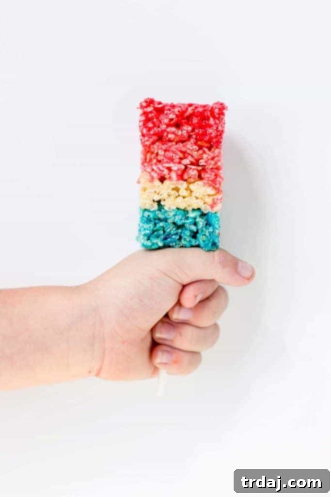 Freedom Fluffs 8 A child's hand reaching for a Patriotic Crispy Treat on a stick, highlighting its kid-friendly appeal.