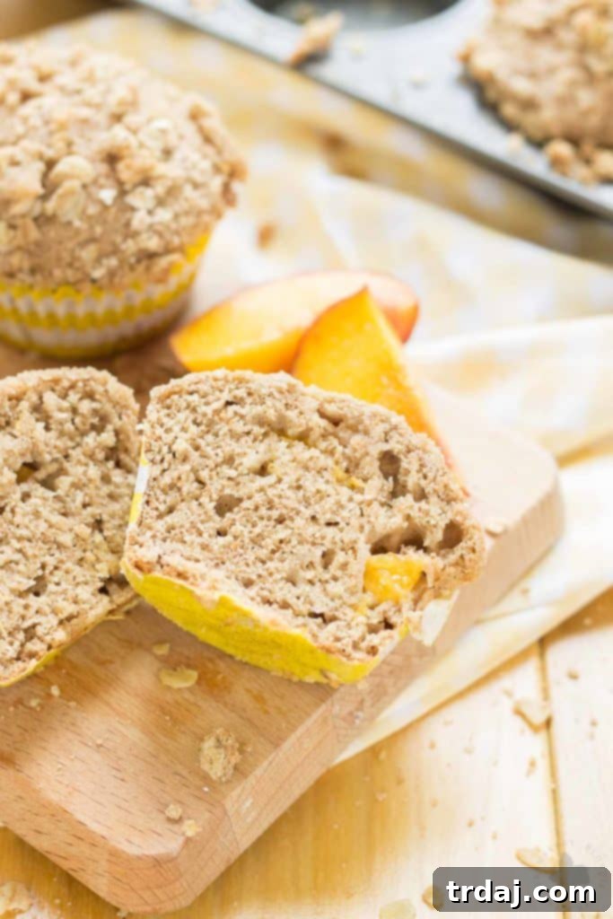 Freshly baked Peach Oatmeal Crumb Muffins on a cooling rack, showcasing their golden-brown topping and soft, peach-filled interior. | Strawberry Blondie Kitchen