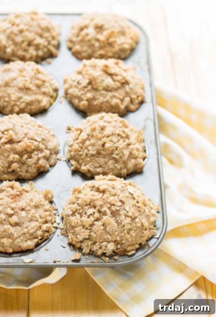 A close-up of a Peach Oatmeal Crumb Muffin, revealing the tender crumb, peach chunks, and generous, crunchy oat topping. | Strawberry Blondie Kitchen