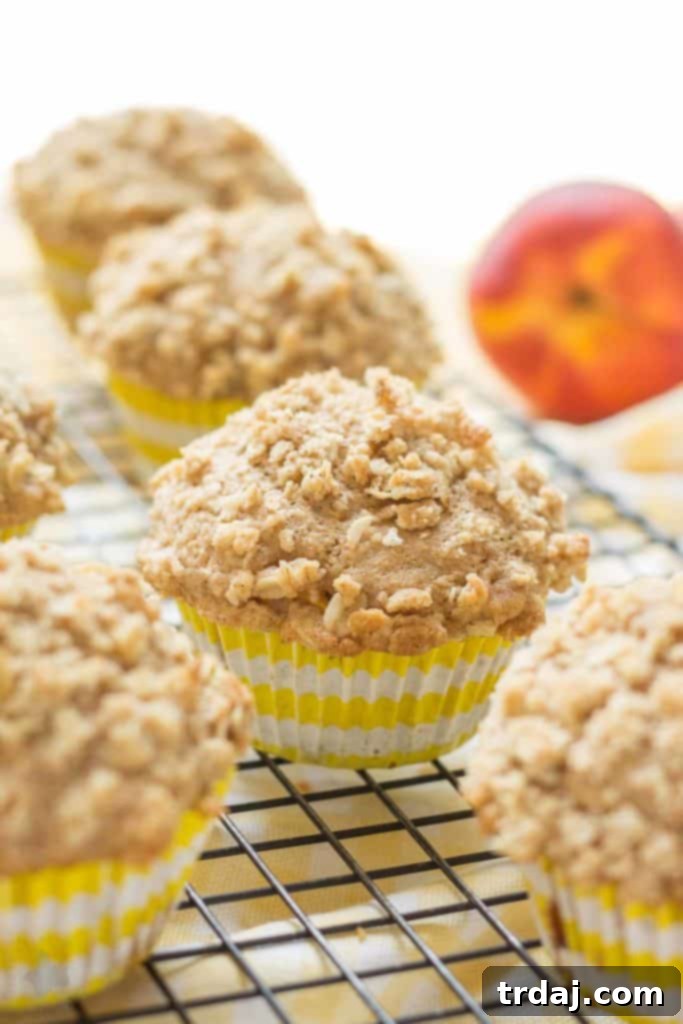 A plate of freshly baked Peach Oatmeal Crumb Muffins, showcasing their golden tops and appealing texture. | Strawberry Blondie Kitchen