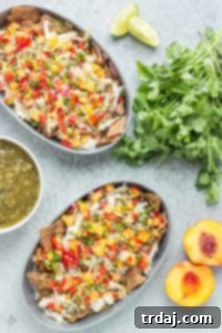 Chicken Nachos with Peach Salsa are bursting with bright summer flavors. Featuring juicy, ripe peaches, fresh chopped veggies and herbs, perfectly cooked chicken and a homemade tomatillo sauce, these nachos will have skipping the taco stand! | Strawberry Blondie Kitchen