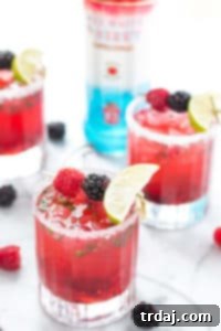 A hybrid between a mojito and a classic martini, this Triple Berry Mojitini is patriotism in a glass. Muddled mint, sugar and berries combine with limeade and Smirnoff Red White and Berry to bring you this refreshing cocktail perfect for all your outdoor parties! | Strawberry Blondie Kitchen