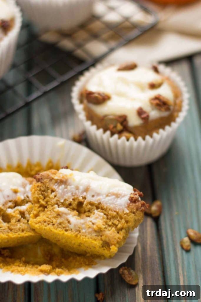 Close-up shot of a freshly baked Pumpkin Spice Cream Cheese Muffin, showing the rich cream cheese swirl and crunchy pepitas. | Strawberry Blondie Kitchen