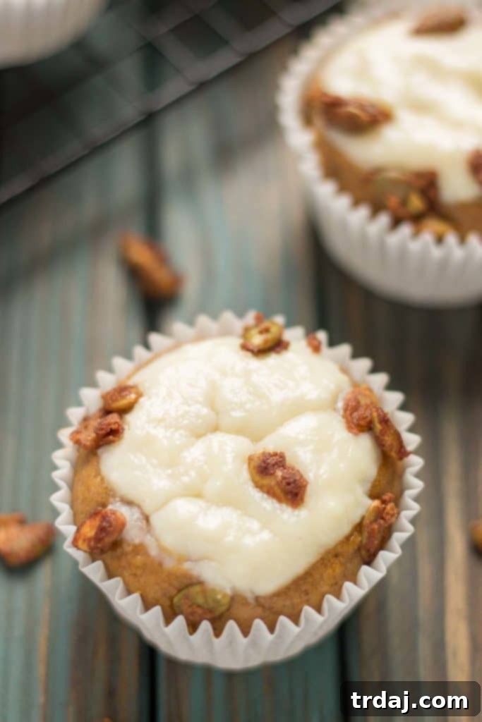 A close-up of a Pumpkin Spice Cream Cheese Muffin, highlighting the creamy, melted cream cheese swirl on top. | Strawberry Blondie Kitchen