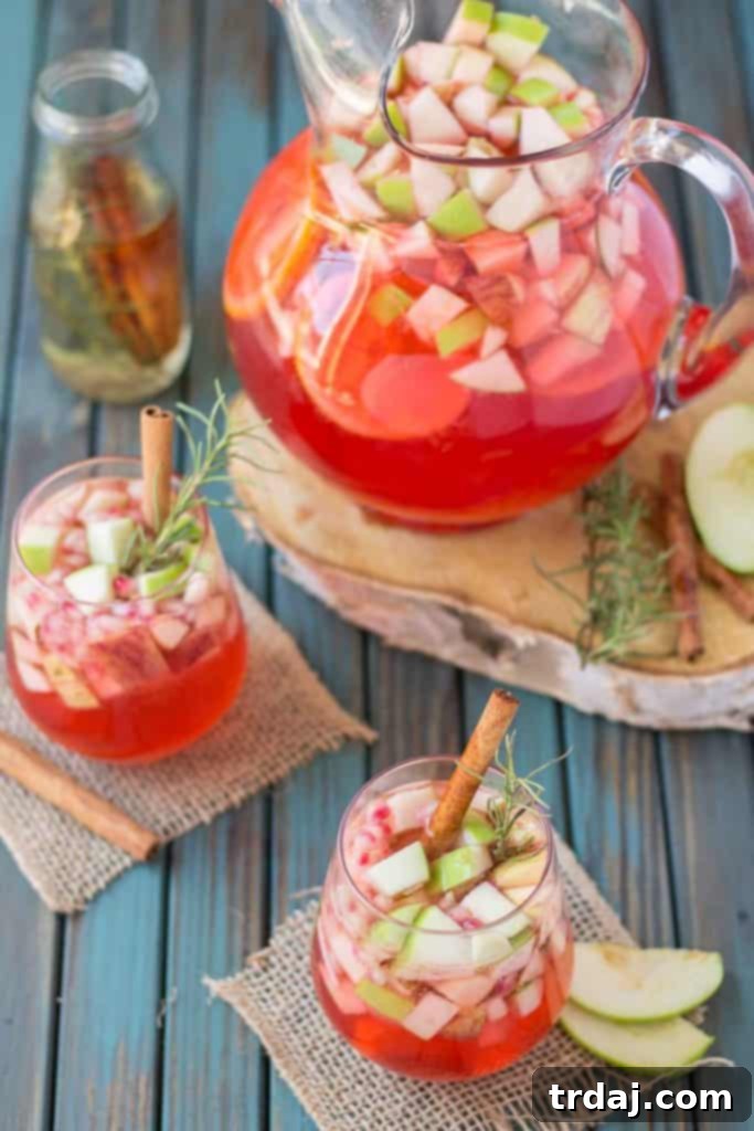 Cranberry Apple Rosemary Sangria glasses garnished with cinnamon sticks and rosemary sprigs, ready to be enjoyed in an autumn setting.