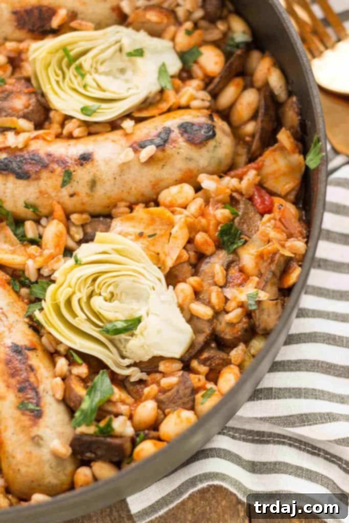 Overhead view of a vibrant One-Pan Tuscan Italian Sausages dish in a skillet, showcasing the rich tomato sauce, sausages, beans, and fresh herbs.