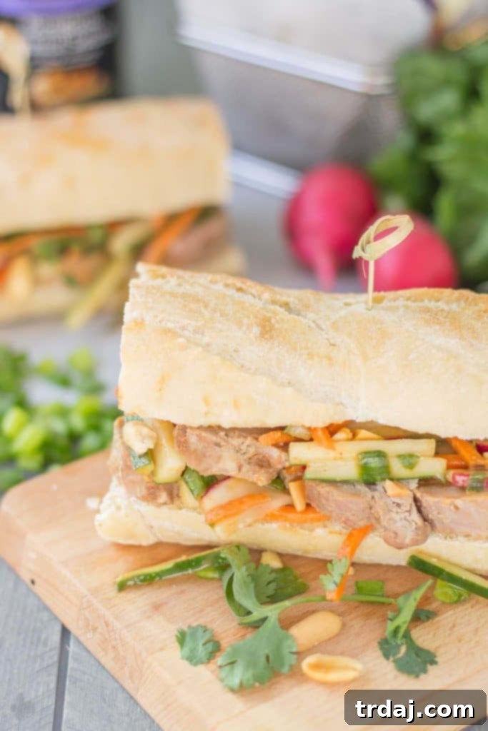 Assembling a Banh Mi sandwich with sliced pork, peanut coleslaw, and fresh herbs