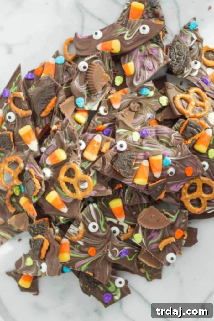 Monster Mash Bark 4 Child's hand reaching for a piece of Halloween Candy Bark, showcasing the colorful array of toppings.