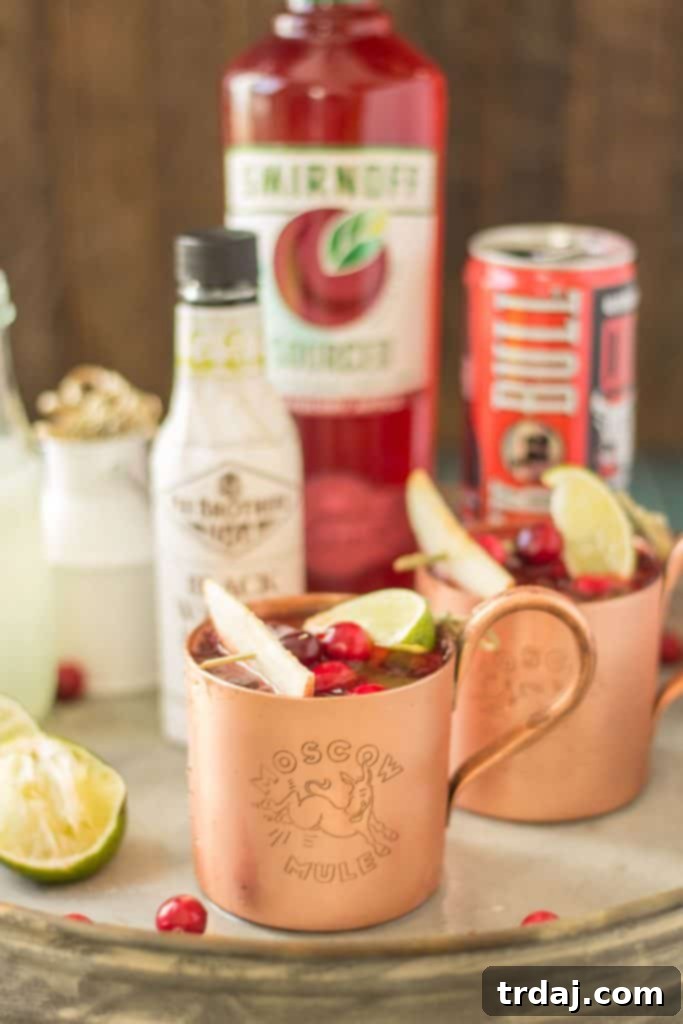 Cranberry Apple Moscow Mule served in a copper mug with cranberries and lime, perfect for fall parties and festive gatherings.