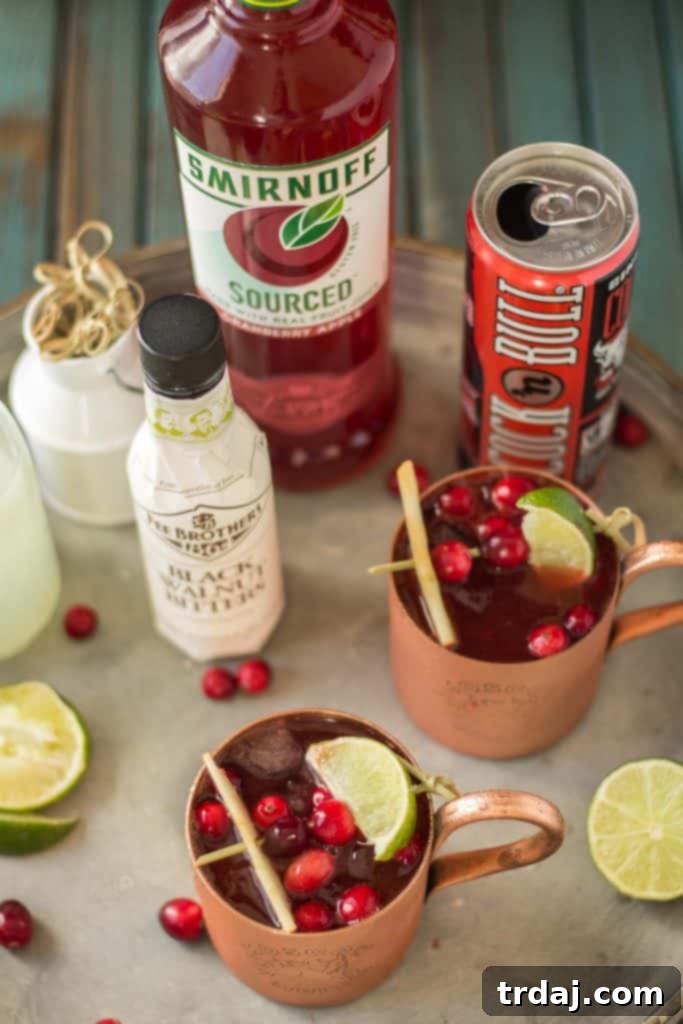 A copper mug of Cranberry Apple Moscow Mule with a garnish of lime slices and frozen cranberries on a rustic wooden surface, perfect for an autumn evening.