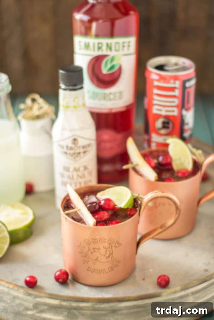 Two hands holding copper mugs of Cranberry Apple Moscow Mules, toasting to the autumn season and holiday spirit.