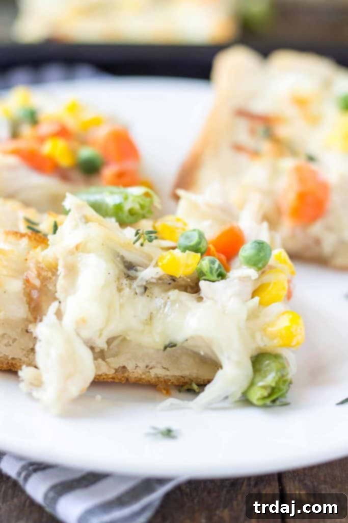 Turkey Pot Pie Pizza Bake 3 A close-up shot of the mouthwatering Leftover Turkey Pot Pie Slab Pizza, showcasing its generous layers of cheese, tender turkey, and colorful vegetables, perfect for any gathering. | Strawberry Blondie Kitchen