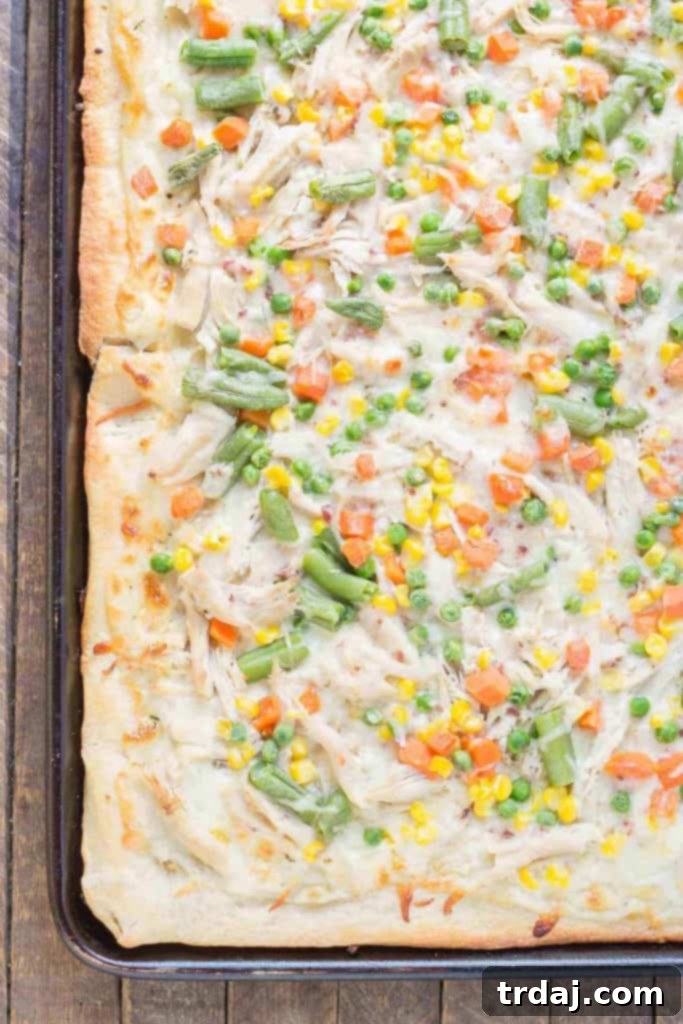 Turkey Pot Pie Pizza Bake 4 Close-up of a slice of Leftover Turkey Pot Pie Slab Pizza, showcasing the rich, creamy texture and abundant toppings, a perfect way to enjoy Thanksgiving leftovers. | Strawberry Blondie Kitchen