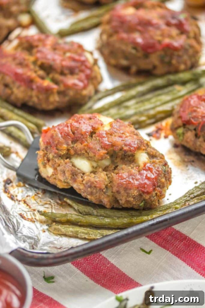 Sheet Pan Mini Meatloaves with Potatoes and Green Beans: A flavorful and convenient one-pan meal that simplifies dinner time. A close-up view of golden-brown mini meatloaves, roasted potatoes, and green beans cooking together on a sheet pan, ready for the oven.