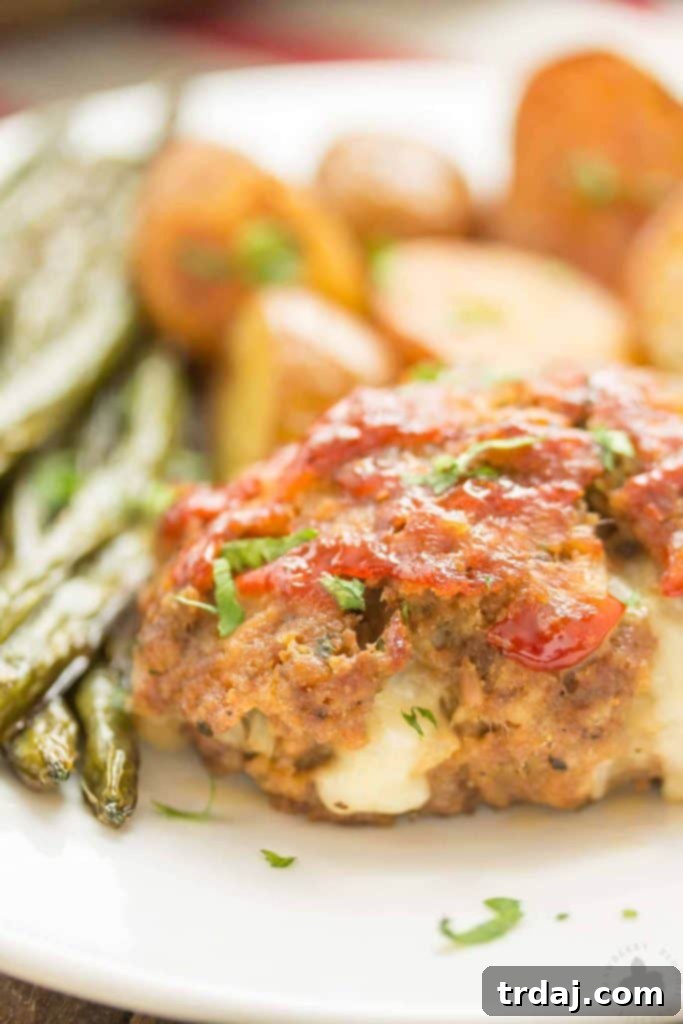 Sheet Pan Mini Meatloaves with Potatoes and Green Beans: Discover the delightful melted cheese core in every tender meatloaf. A close-up of a mini meatloaf cut open, revealing the melted white cheddar cheese center, highlighting the delicious surprise within.