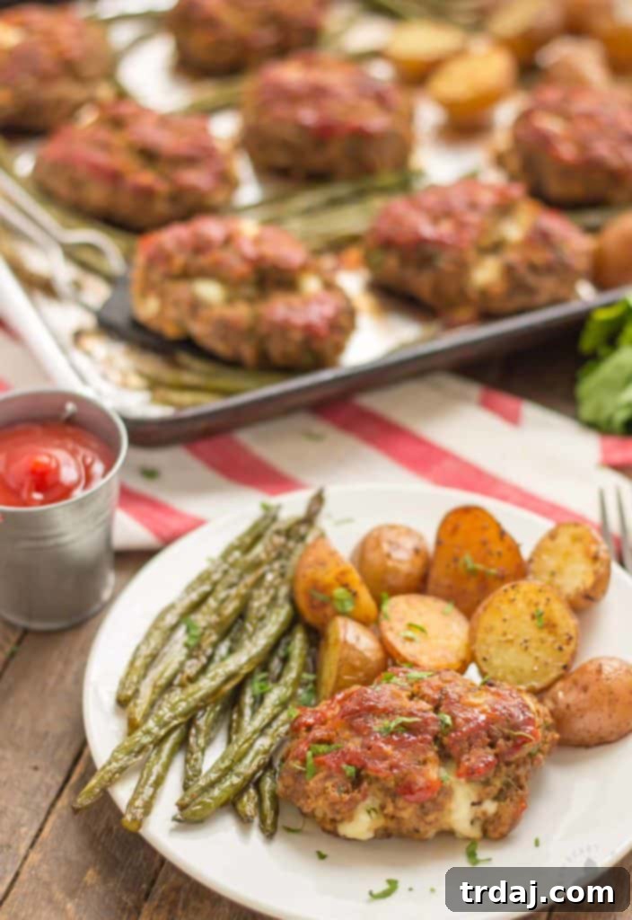 Sheet Pan Mini Meatloaves with Potatoes and Green Beans: A delightful comfort food meal, perfectly served with a touch of ketchup for added flavor. A beautifully plated serving of Sheet Pan Mini Meatloaves with Potatoes and Green Beans, accompanied by a small side of ketchup, ready to be enjoyed.