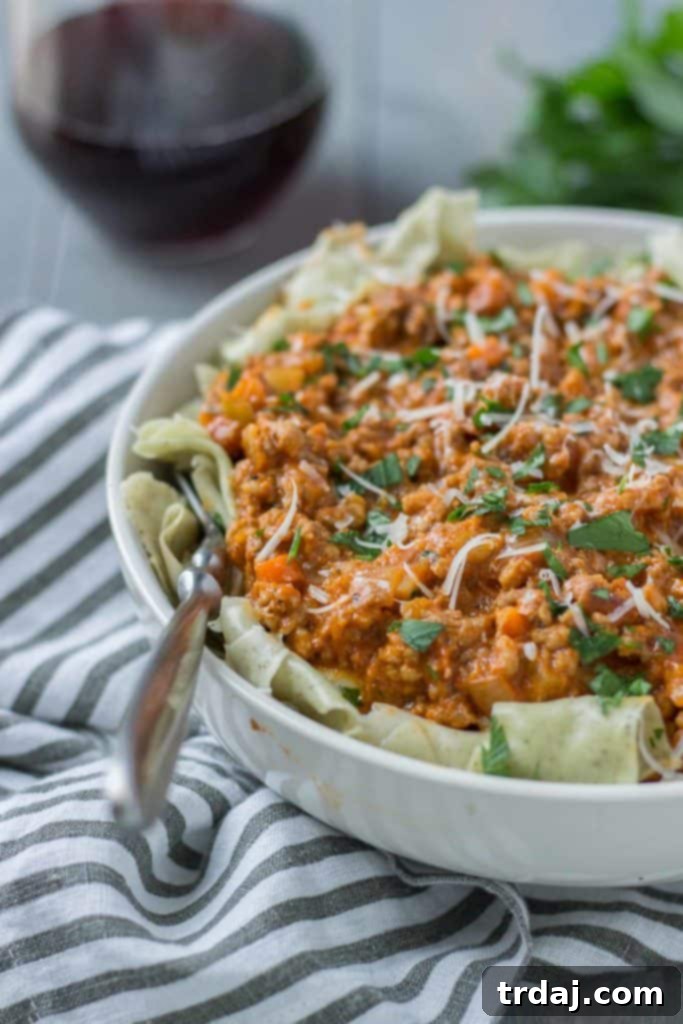 Close-up of a bowl of Beef Ragu with Pappardelle, topped with grated Parmesan cheese.