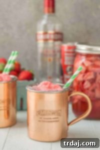 A refreshing Strawberry Moscow Mule Float with homemade strawberry vodka and sorbet, garnished with lime and strawberries.