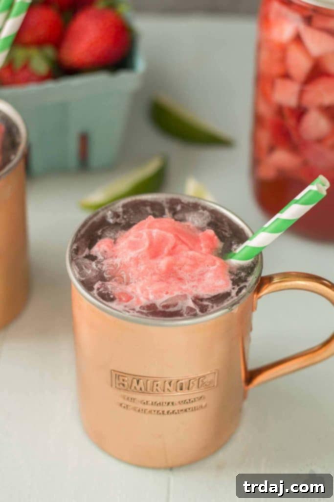 A refreshing Strawberry Moscow Mule Float with homemade strawberry vodka and sorbet, garnished with lime and strawberries, ready to be enjoyed.