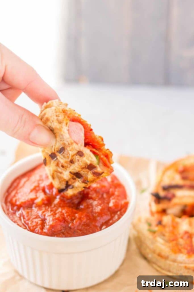 Waffle Pizza Pockets 7 A beautifully arranged plate featuring several triangular Pizza Wafflewiches, cut in halves to show the melted cheese and toppings, accompanied by a small bowl of pizza sauce for dipping. | Strawberry Blondie Kitchen