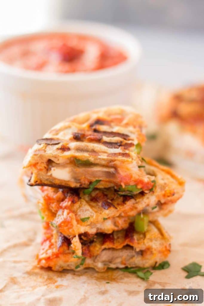 Waffle Pizza Pockets 9 A close-up of a perfectly toasted Pizza Wafflewich, cut into a triangle, showing the melted cheese and pepperoni, presented on a white plate ready to be enjoyed. | Strawberry Blondie Kitchen