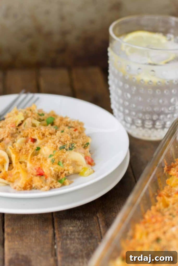 A serving of Lightened Up Cheesy Tuna Noodle Casserole with a fork, showing the creamy noodles, tuna, and vegetables.