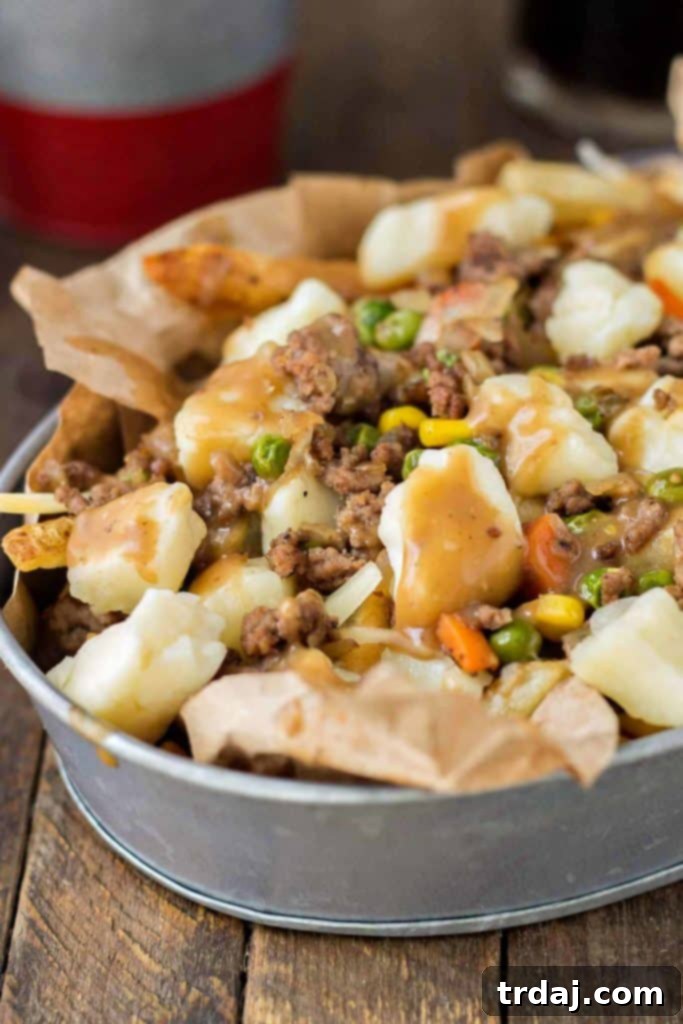 Crispy fries piled high with beef and mixed vegetables, smothered in Guinness gravy and topped with cheese curds make for one awesome Shepherd's Pie Poutine. | Strawberry Blondie Kitchen