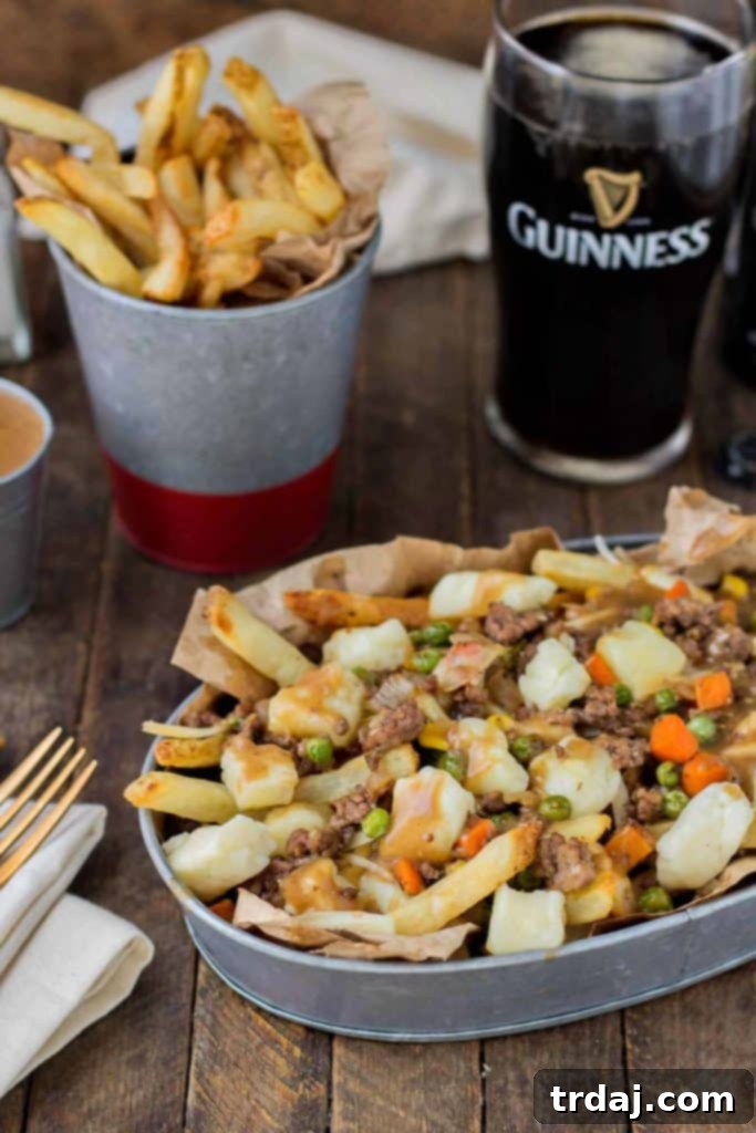 Crispy fries piled high with beef and mixed vegetables, smothered in Guinness gravy and topped with cheese curds make for one awesome Shepherd's Pie Poutine. | Strawberry Blondie Kitchen