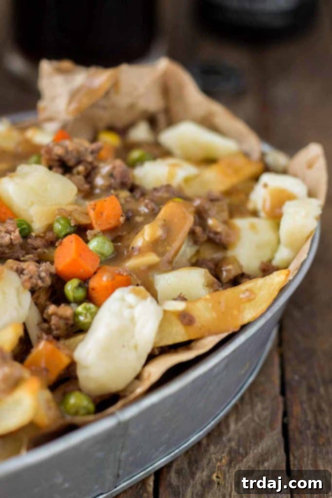 Crispy fries piled high with beef and mixed vegetables, smothered in Guinness gravy and topped with cheese curds make for one awesome Shepherd's Pie Poutine. | Strawberry Blondie Kitchen