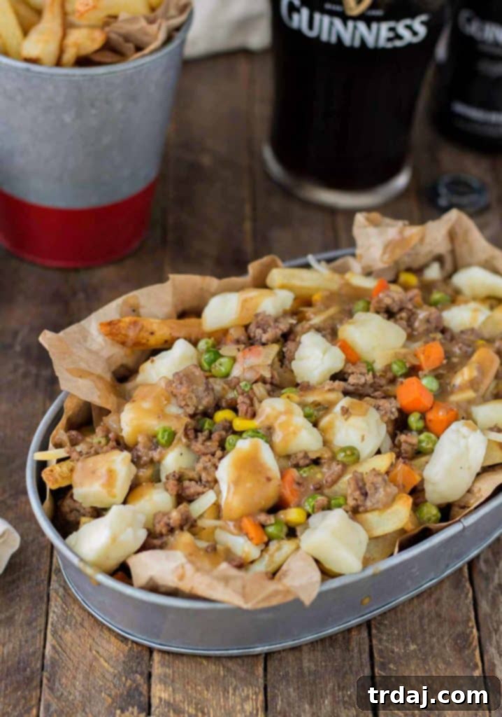 Crispy fries piled high with beef and mixed vegetables, smothered in Guinness gravy and topped with cheese curds make for one awesome Shepherd's Pie Poutine. | Strawberry Blondie Kitchen