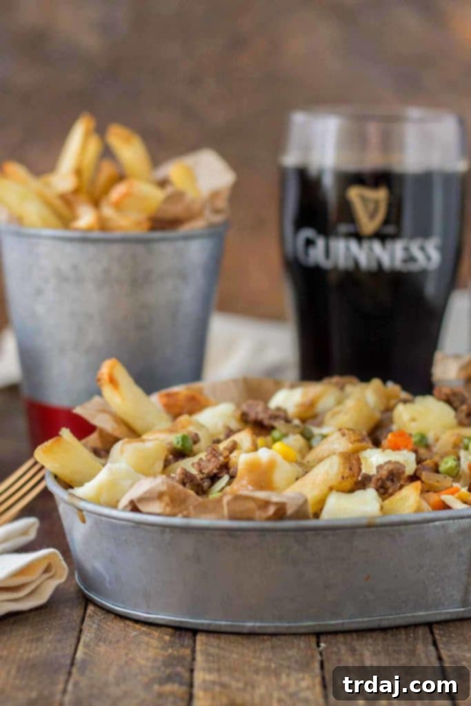 Crispy fries piled high with beef and mixed vegetables, smothered in Guinness gravy and topped with cheese curds make for one awesome Shepherd's Pie Poutine. | Strawberry Blondie Kitchen