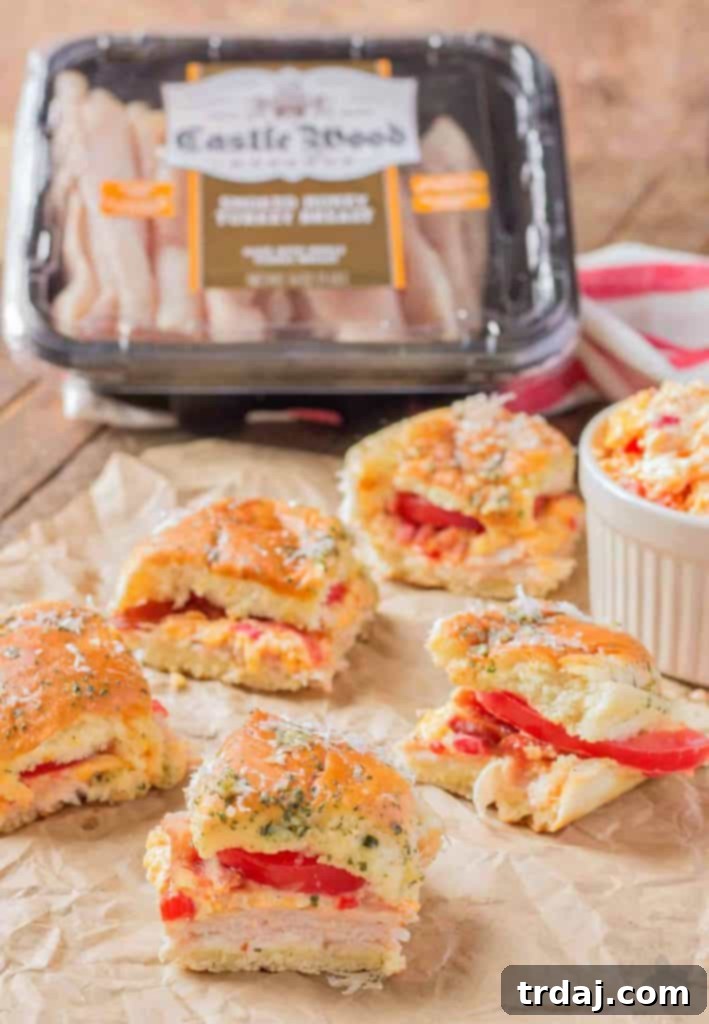 The perfect appetizer for any event: Delicious Kentucky Hot Brown Turkey Sliders with Castle Wood Reserve® honey turkey, pimento cheese, bacon, and tomatoes. A top-down view of multiple Kentucky Hot Brown Turkey Sliders, highlighting their golden crust and savory fillings, ready for a gathering.