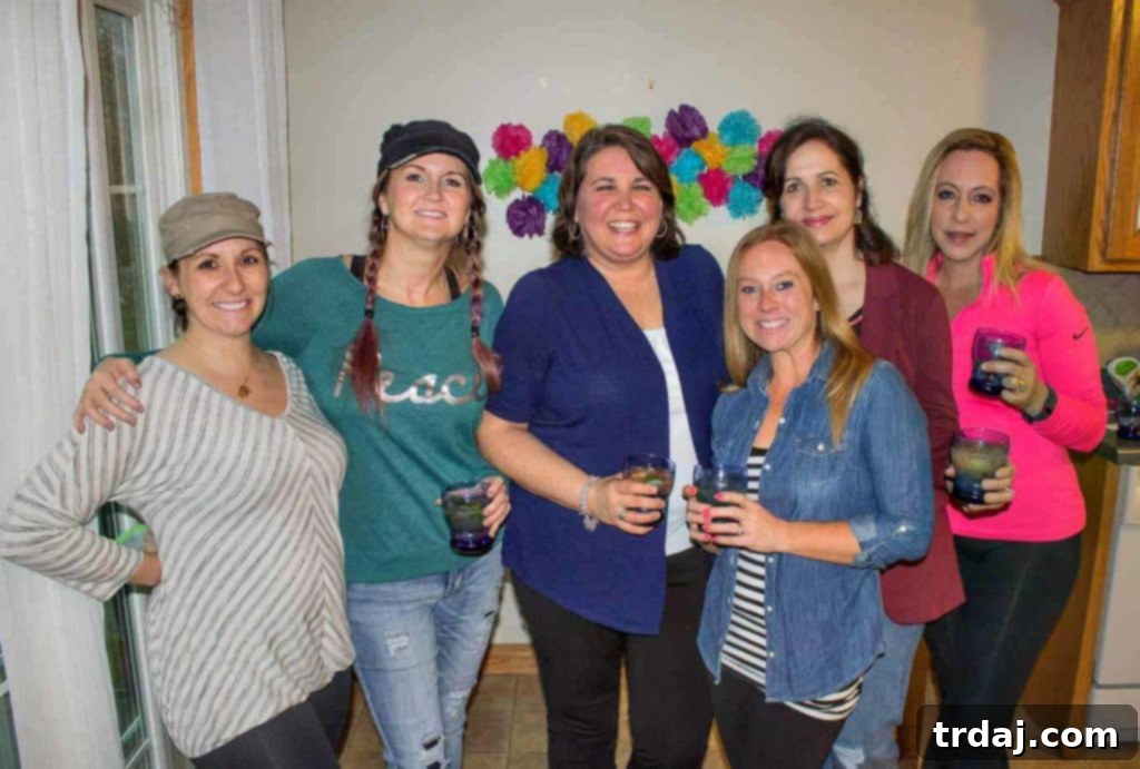Smiling friends enjoying a vibrant outdoor Cinco de Mayo fiesta, raising their Sauza margaritas in a toast to good times and celebrations.
