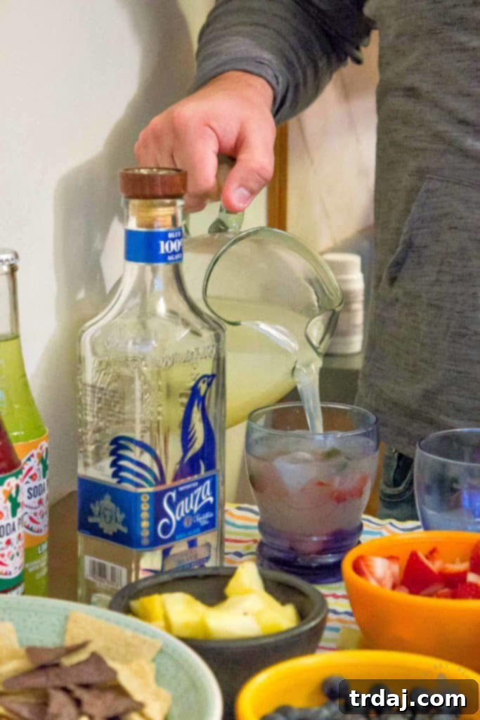 A refreshing pitcher of Sauza margaritas with lime and ice, ready to be served, highlighting the ease of hosting with pre-mixed drinks.