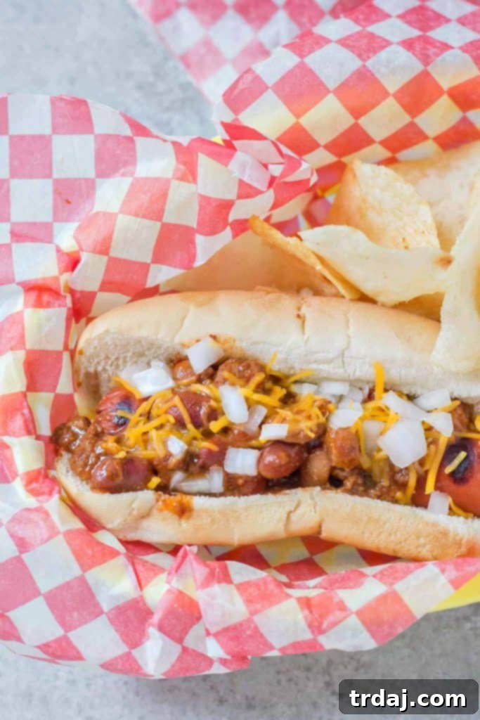 Effortless Chili Dogs 3 Close-up of an Easy Chili Dog, showcasing the delicious chili and melted cheese over a grilled hot dog in a soft bun.