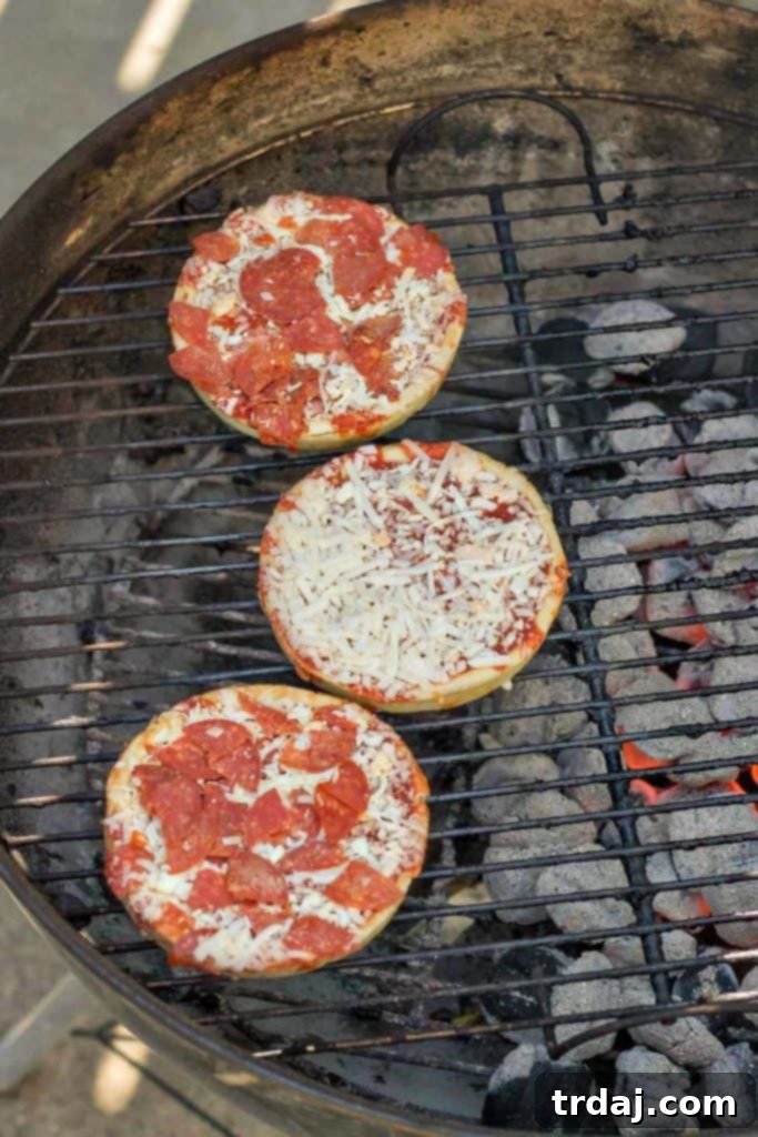 Three grilled Red Baron Deep Dish Pizzas lined up on a serving platter at a casual outdoor party.