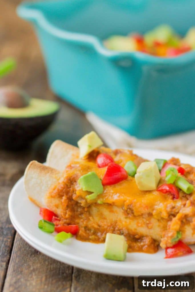 A close-up of a single Chipotle Chicken Enchilada, beautifully golden and topped with melted cheese.