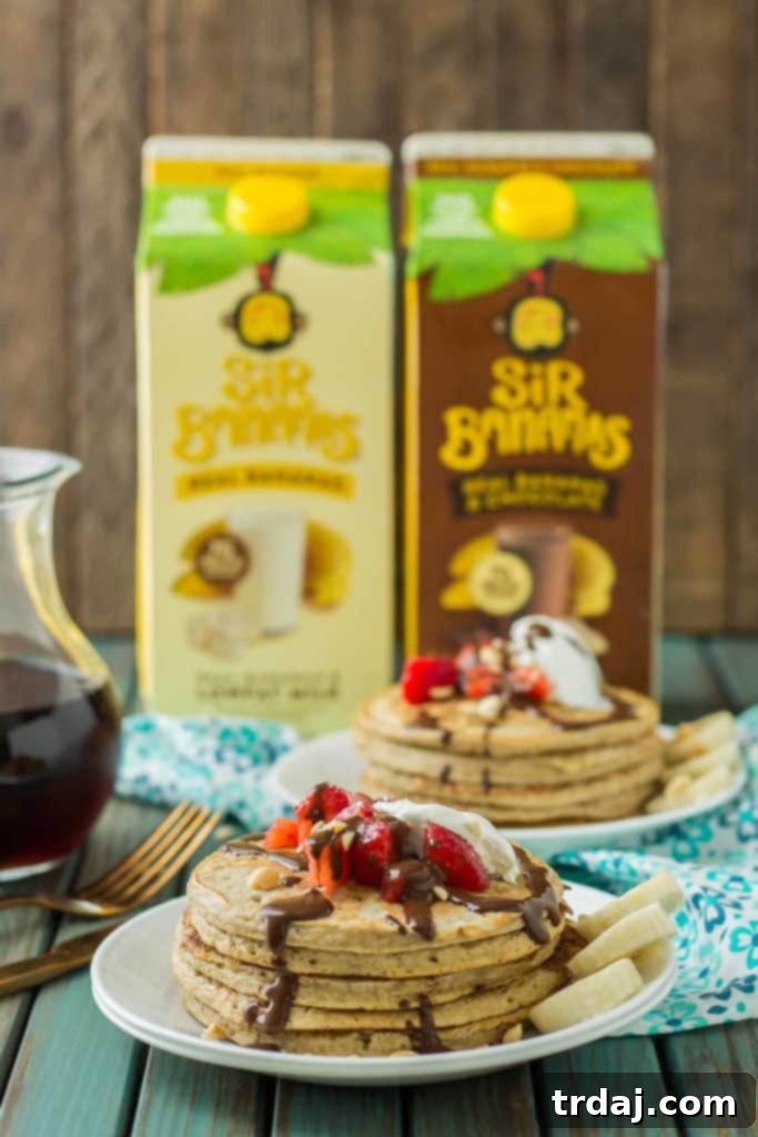 Delicious stack of Banana Split Pancakes topped with fresh fruit, chocolate syrup, whipped cream, and nuts, perfect for a breakfast treat.